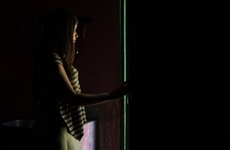 Adolescente en la oscuridad mirando una puerta