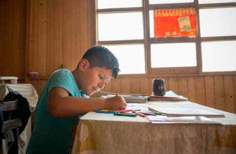 Niño sentado en una mesa coloreando un libro